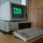 A fairly standard IBM PC of the era. This one has a green monitor, a disk drive and a keyboard.